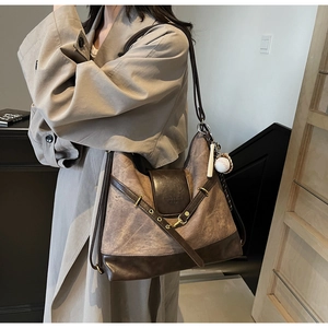 Detail of vintage brown leather tote bag showing V-shaped buckle and embossed flap texture
