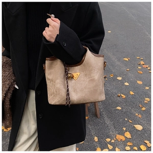 Photo de sac cabas kaki avec bordure en cuir et plaque triangulaire dorée dehors
