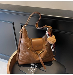 Close-up of retro brown leather tote bag with gold swivel lock and plush bear charm