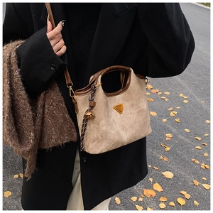 Détail du sac cabas en daim kaki avec poignées en cuir marron et pendentif décoratif