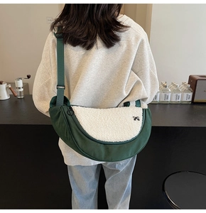 Detail of green crossbody crescent bag with fleece flap and cute black bow