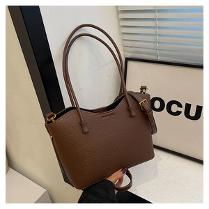 Détail d'un sac cabas marron à motif litchi avec ferrures dorées et double bandoulière