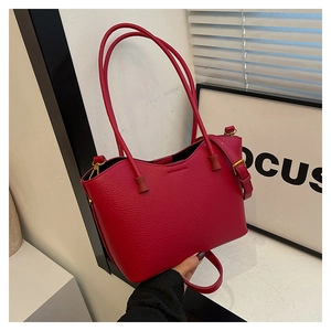 Détail d'un sac cabas en cuir rouge grainé avec ferrures dorées et bandoulière réglable
