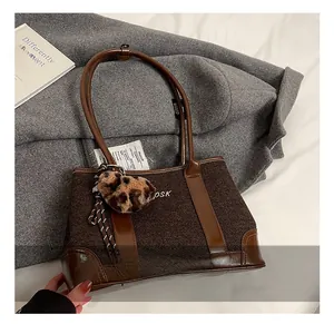 Detail of tweed tote bag with leather trim, OSK logo, and leopard heart charm
