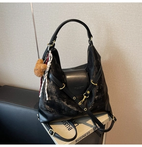 Detail of black suede hobo bag with gold texture and cute brown plush bear charm