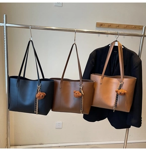 Vue détaillée de trois sacs cabas classiques en noir, café et caramel avec breloques d'ours