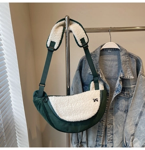 Detail of dark green corduroy dumpling bag with white fleece patch and bow accent