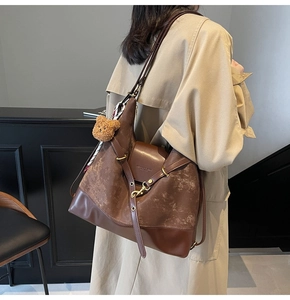 Detail of vintage brown leather tote with plush bear charm and adjustable strap