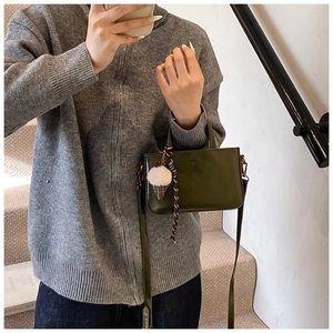 Détail du sac à main vert olive avec charm en peluche et cordon de suspension tissé