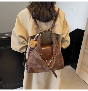 Detail of dark brown faux suede tote bag with bear charm and scarf on a model