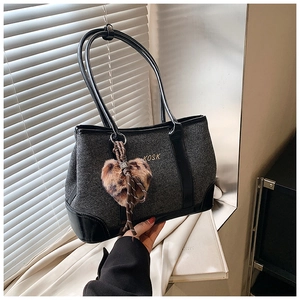 Detail of grey woven tote bag with leather straps and leopard heart plush charm