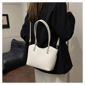 Détail du sac cabas en cuir grainé crème avec un design unique à bordure ondulée