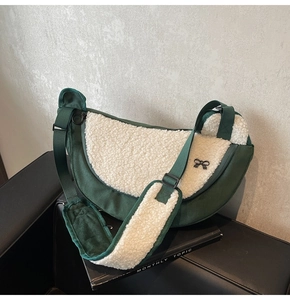 Detail of green canvas and creamy fleece crescent bag with a small bow decoration
