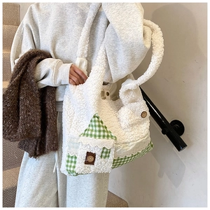 Detailansicht der weißen Lammfell-Tasche mit dekorativem Haus-Patch und Spitzenbesatz
