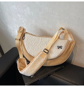 Detail of plush crescent crossbody bag featuring cream suede and white faux shearling fabric