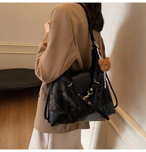 Detail of black patchwork tote bag with adjustable strap and brown bear charm on a model