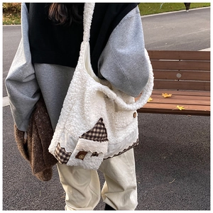 Detail der weißen Lammfell-Tasche mit dekorativem hausförmigem Patchwork aus Stoff