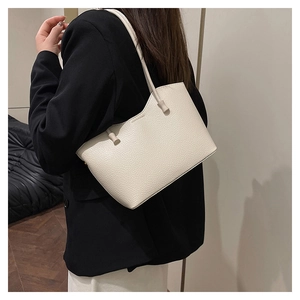 Détail du grand sac cabas en cuir crème porté à l'épaule dans un décor minimaliste épuré