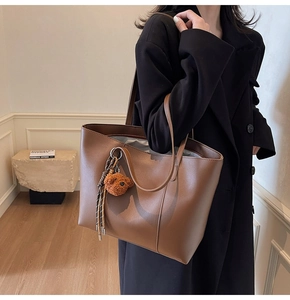 Detailaufnahme einer braunen Vintage-Ledershopper mit Bärenanhänger und weichem Innenfutter