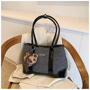 Detail of grey textured large tote bag with black glossy trim and leopard faux fur charm
