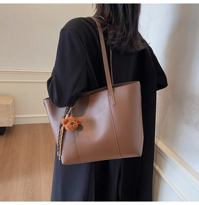 Sac cabas marron porté par un mannequin, vue de profil avec pendentif ours en peluche