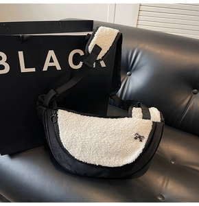 Detailed view of plush black and white crescent crossbody bag with a bow accent