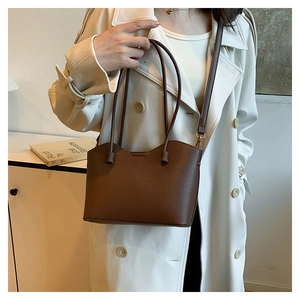 Gros plan du sac en cuir marron à motif litchi avec des détails dorés sur un modèle
