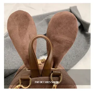 Détail du sac à dos en daim marron avec oreilles de lapin et fermetures dorées