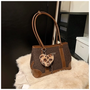 Close-up of large brown tweed tote bag with leather handles and leopard heart charm