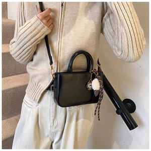 Détail du sac à main en cuir noir avec pendentif en métal et ruban à carreaux