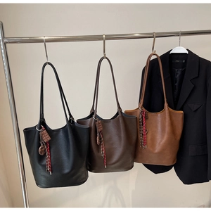 Détail de grands sacs seaux en cuir de couleur noire, café foncé et marron caramel élégants