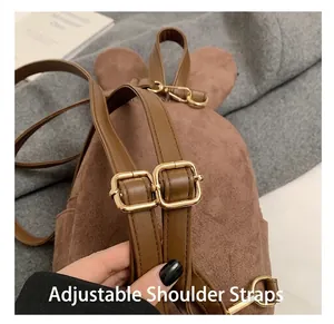 Détail des bretelles réglables en cuir marron et boucle dorée sur sac à dos daim