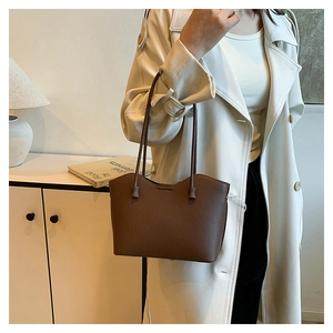 Gros plan du sac fourre-tout marron en cuir texturé sur mannequin en studio épuré