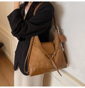 Detail of brown suede hobo bag featuring decorative ribbons, silk scarf, and metal buckle