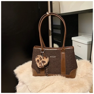 Close-up of brown tweed tote bag with KOSK logo and leopard print heart charm