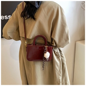 Dettaglio della borsa in pelle cerata rosso scuro con elegante ciondolo in peluche a gelato