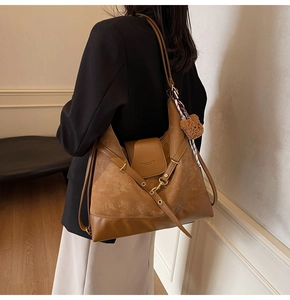 Detail of a brown leather tote bag with plush bear charm and silk scarf on a model