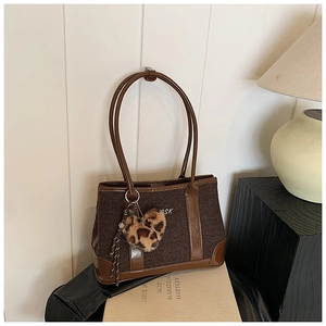 Detail of retro dark brown shoulder bag with OSK embroidery and leopard heart charm