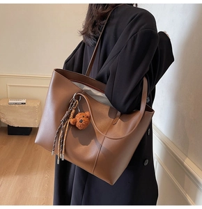 Gros plan détaillé du sac cabas en cuir marron foncé avec charm ours et pompon tissé