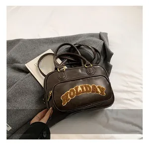 Detail showing dark brown Boston bag with plush Holiday embroidery and golden hardware