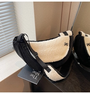 Detail of faux shearling crescent bag with black bow hardware and adjustable strap