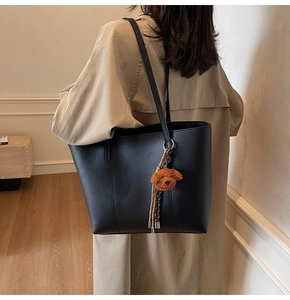 Détail du grand sac cabas noir avec pendentif ours en peluche marron à l'épaule