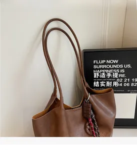Détail d'un sac seau vintage en cuir marron avec pendentif chocolat et bandoulière réglable