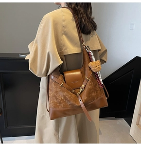 Detail of suede tote bag featuring brown leather patchwork and cute bear pendant charm