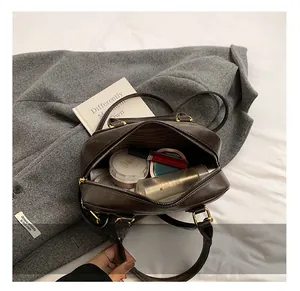 Detail view of the spacious inner compartment with striped lining in a dark brown leather bag
