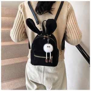 Détail du mini sac à dos noir à oreilles de lapin avec un pendentif poupée en peluche