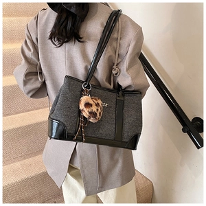 Detail of grey textured fabric tote bag with leopard heart charm and SK logo print