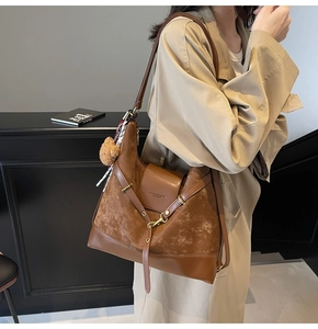 Detail of brown tote bag with suede trim, magnetic flap and plush bear charm