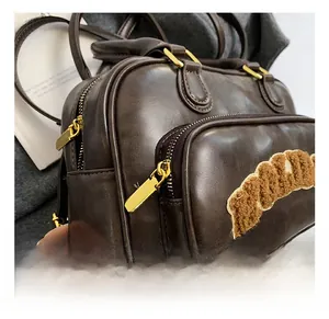 Close-up of vintage brown leather backpack showing gold hardware and plush patch detail