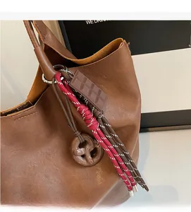 Détail d'un sac seau en cuir marron avec des breloques créatives chocolat et marbre